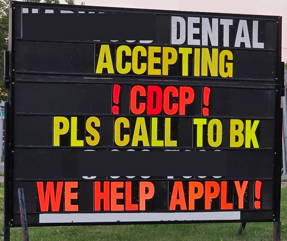 A signboard advertising that a dental clinic participating in the Canadian Dental Care Plan will assist with CDCP applications.