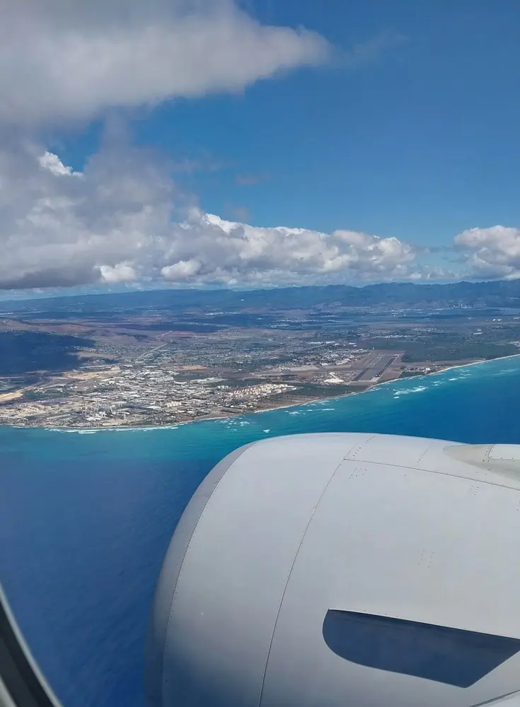 Emerald ocean and the airport runway seen from the airplane window, marking the start of an Oahu Hawaii first day itinerary