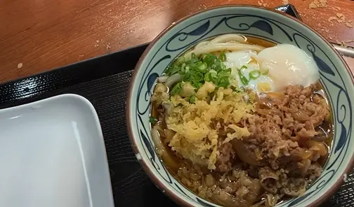 A hot bowl of Nikutama Udon with tender beef and a soft-boiled egg at Marugame Udon on an Oahu Hawaii first day itinerary