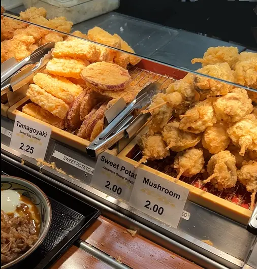 A wide variety of crispy, freshly fried Japanese tempura displayed at the Marugame Udon counter during an Oahu Hawaii first day itinerary
