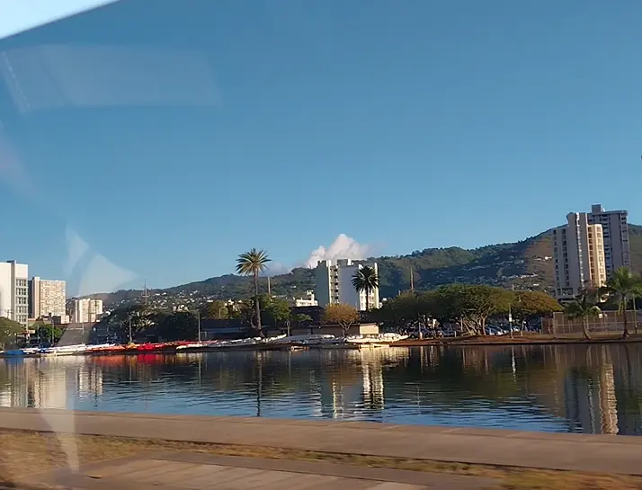 Clear blue sky and green mountain ridges over the Ala Wai Canal seen from the car window while leaving Waikiki for an Oahu North Shore day trip
