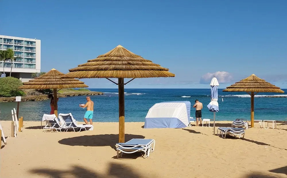 Calm emerald ocean and beach umbrellas under the blue sky at Turtle Bay Resort, a highlight of an Oahu North Shore day trip